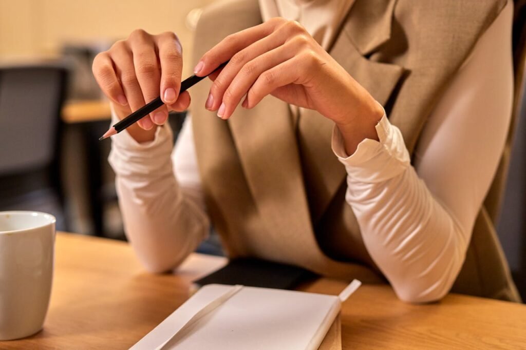 A close-up of a woman holding a pencil at a desk in an office setting.